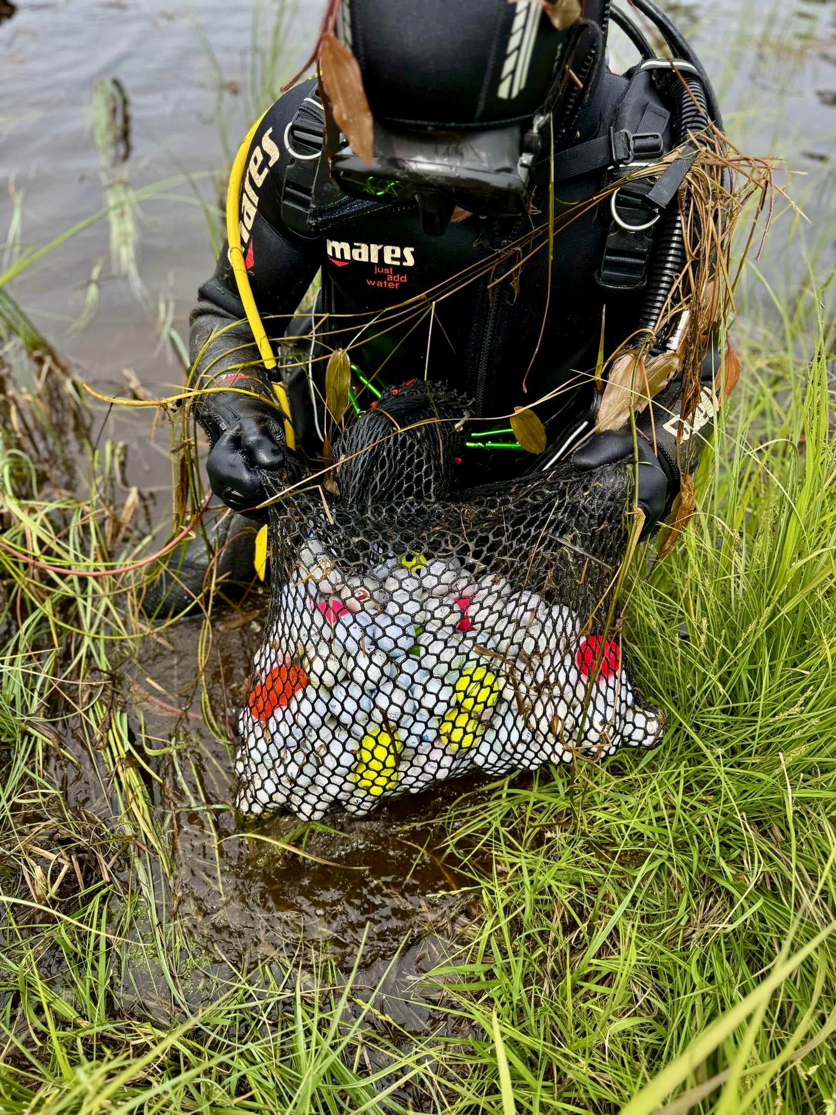 Dykare plockar återvunna golfbollar golfbollar samlade i nätpåse